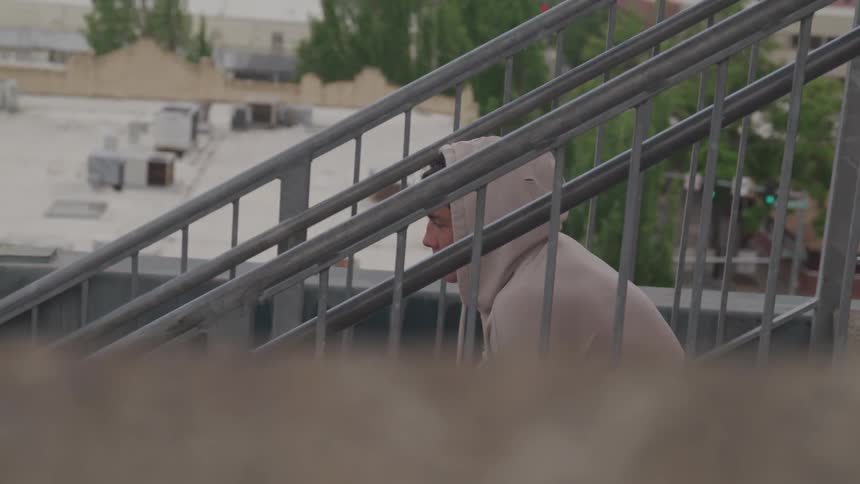 A man with white hoodie sit on the stairs