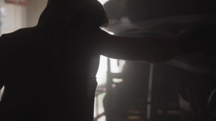Silhouette of a person punching a boxing bag