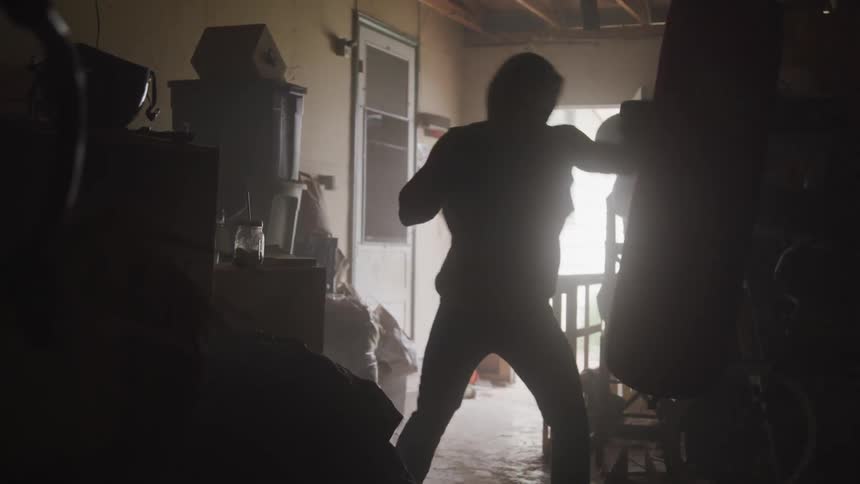 A boxer repeatedly hits a punching bag hanging in a crowded room