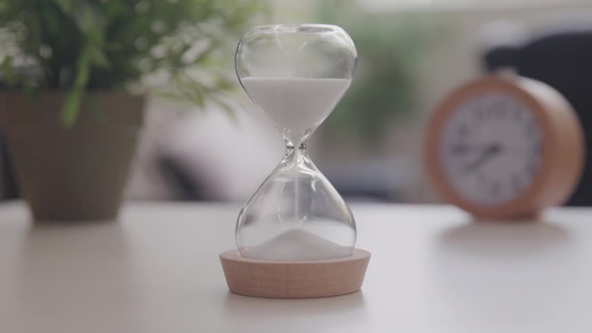 Sand falls through a hourglass on a desk