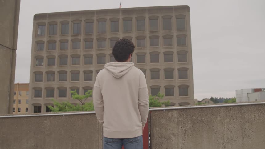 Young man looking out to downtown below from a rooftop deck
