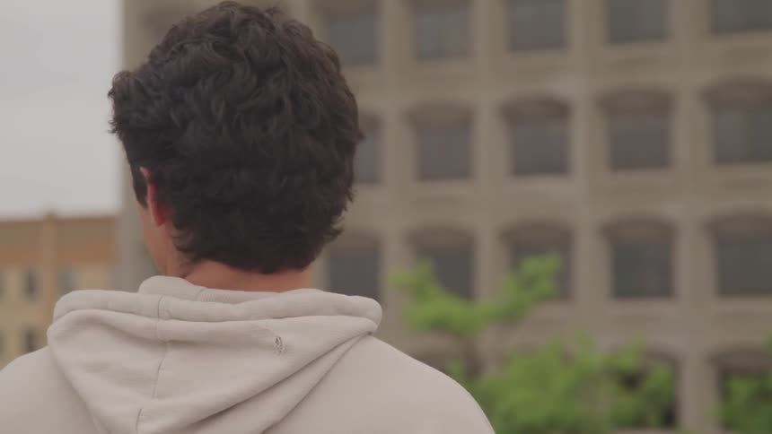 Man wearing a white hoodie looks at the buildings in the city