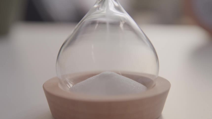 Sand falling from one end of an egg timer to another