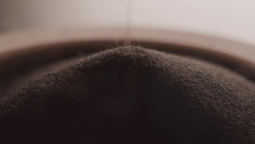 Dark brown grains fall forming mound
