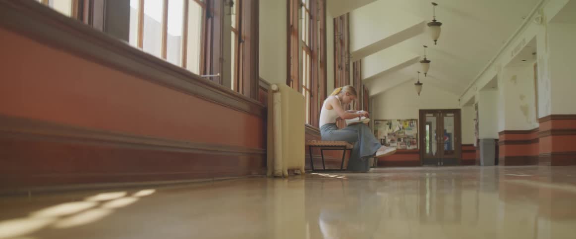A woman is sitting in a building reading a book
