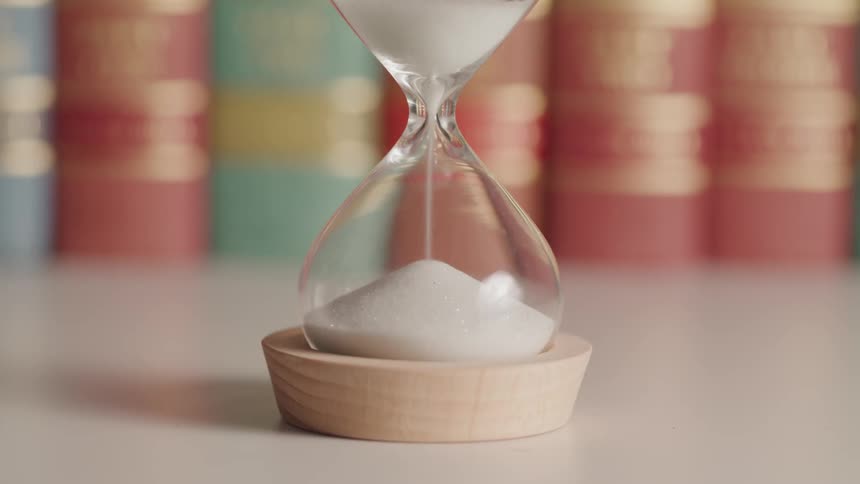 Sand falling from one end of an hourglass to the other