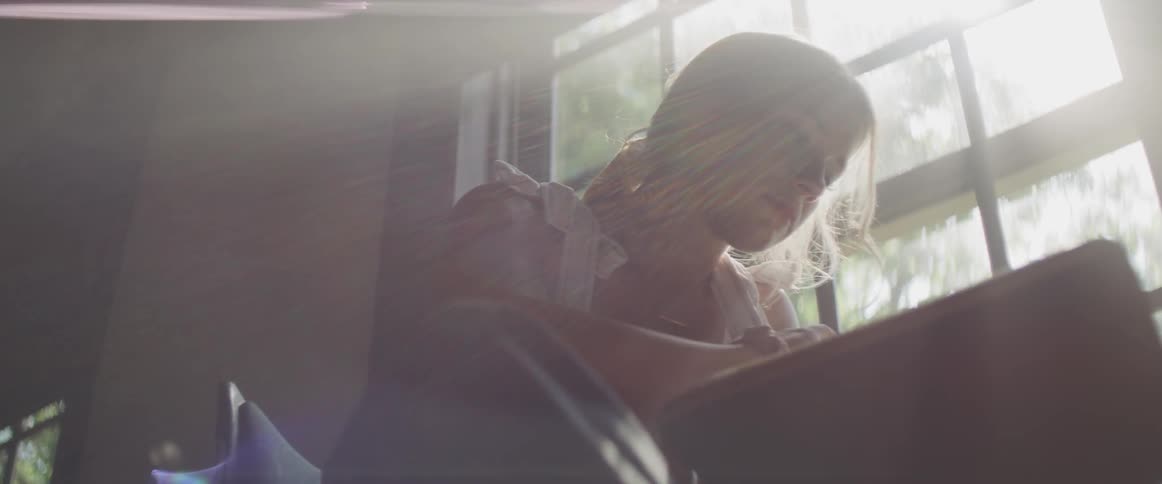 A woman is writing at a desk by the window