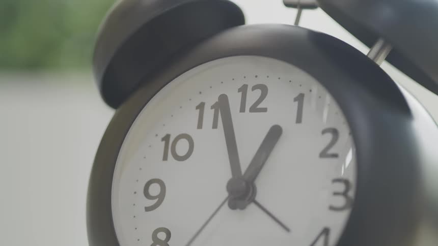 Clock hands move over face of analog alarm clock