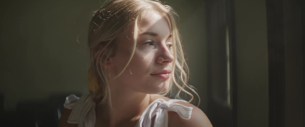Blonde woman looks out the window in a room