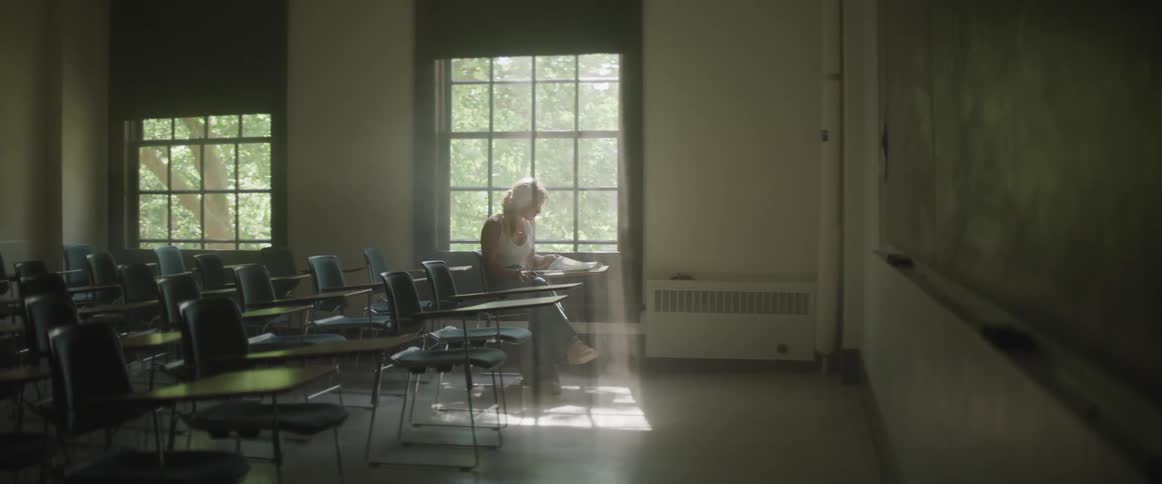 A woman sitting in a classroom reading a book