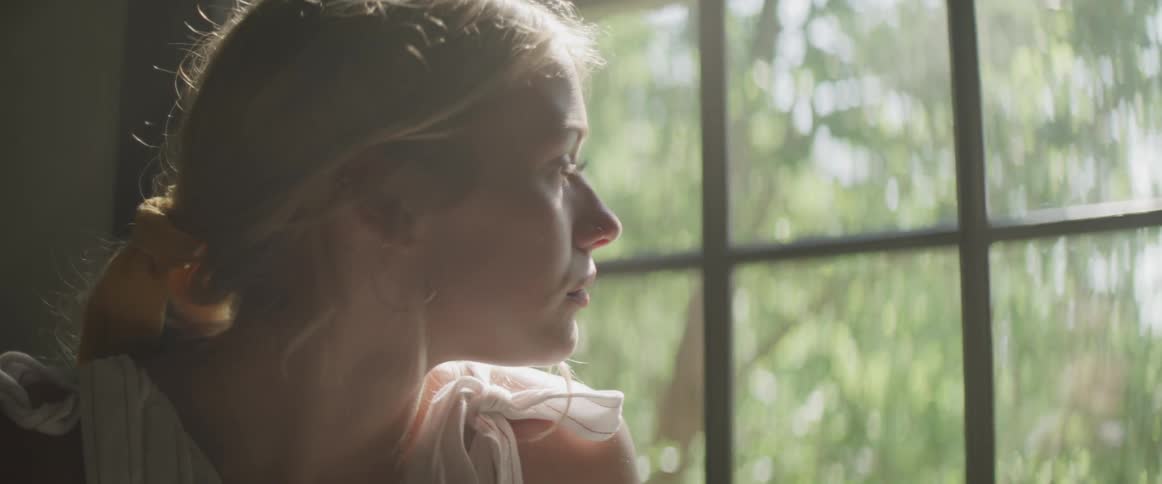A woman sitting down inside looking out of a window