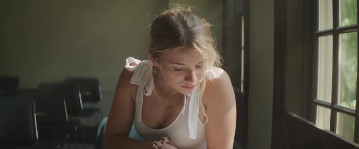 A blonde haired woman working at her desk by a georgian window on a sunny day