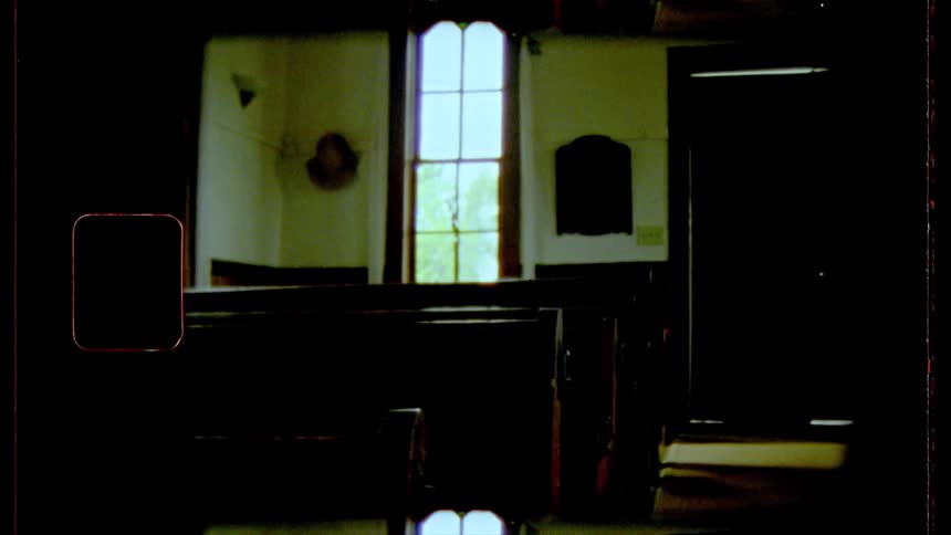 A sun enters a single window the interior of an old church is dimly lit