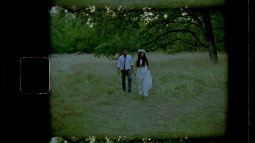 Groom and bride walks on grass in the forest