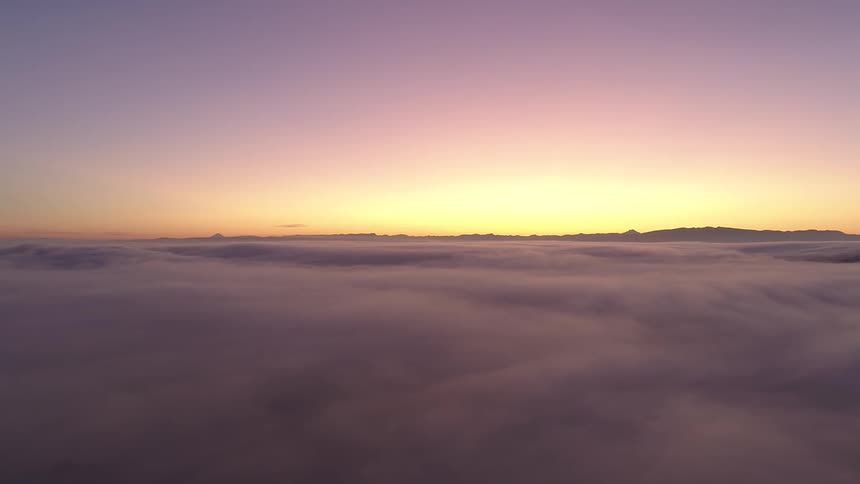 The sun sets on the horizon glowing and coloring a layer of clouds