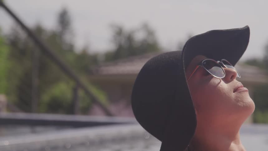 Woman wearing sunglasses looks up at the sunny sky