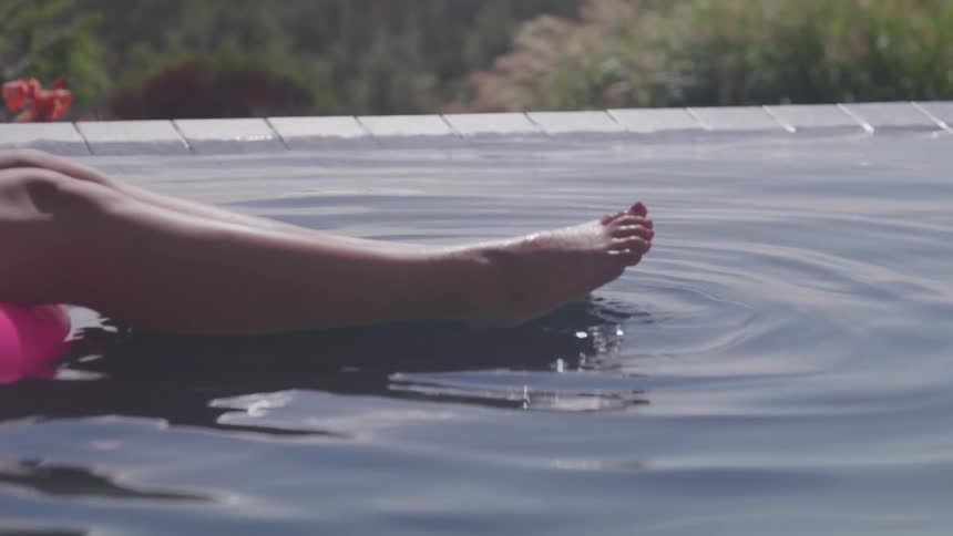 A woman in an infinity pool paddling her feet