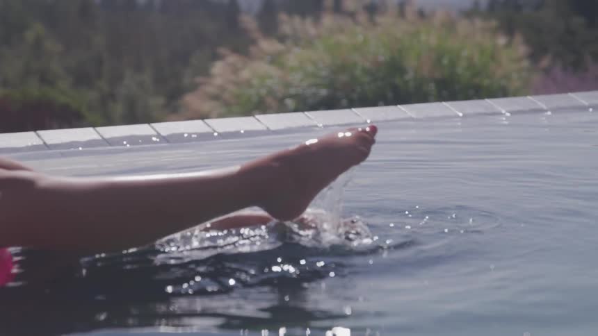 A woman relaxes while floating on an inflatable ring in an infinity pool