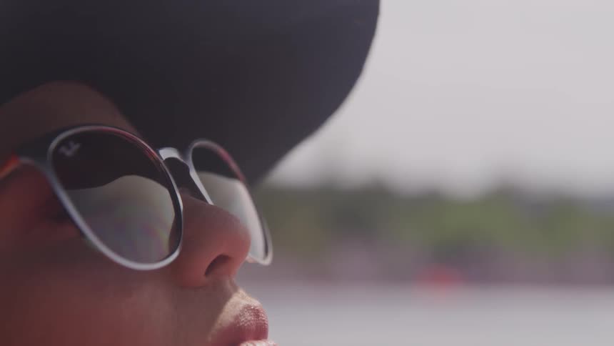 A woman wearing a hat and sunglasses is looking up into the sky