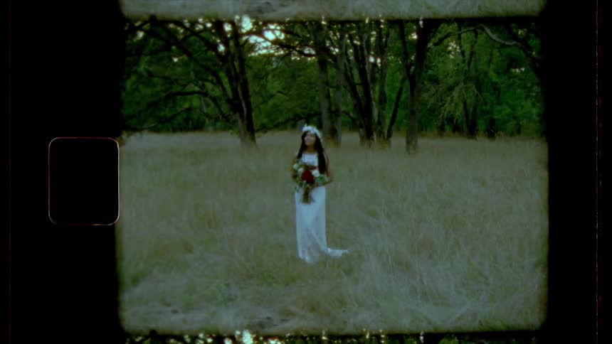 A bride stands in the long grass