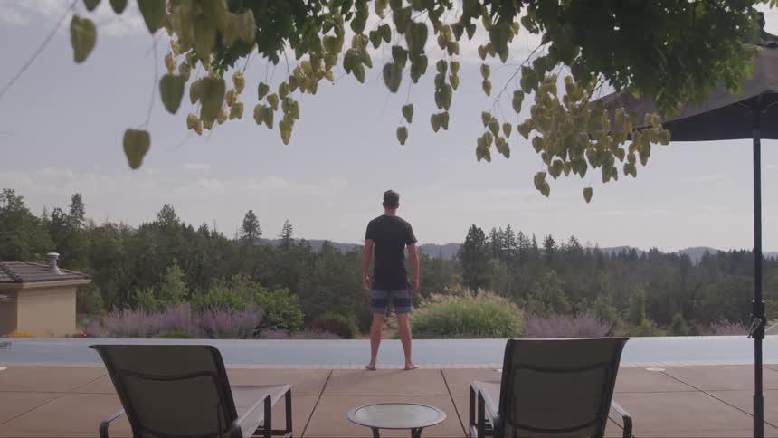 A man is standing outside by his pool