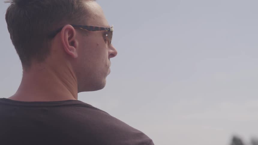 Side profile of a man wearing sunglasses on a sunny day