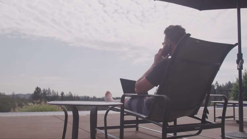 A man sits on the phone and laptop
