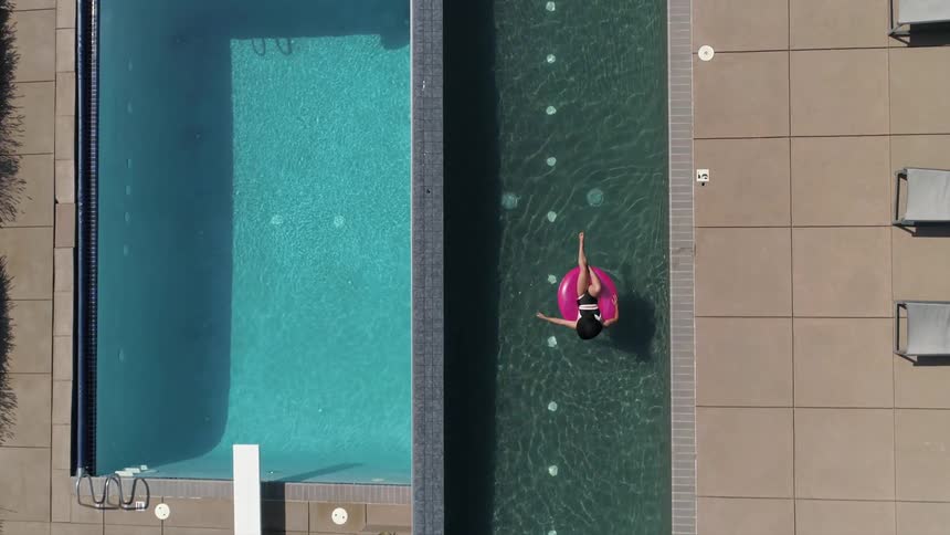 A woman relaxes while floating on an inflatable ring in an infinity pool