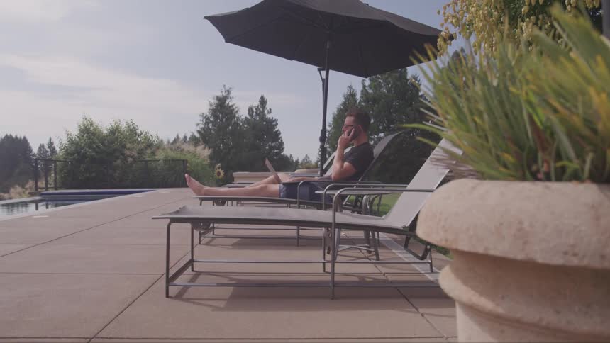 Man sitting on a lounge chair talking on his cell phone