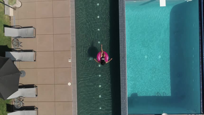Birds eye view of a woman floating in a water above a pool