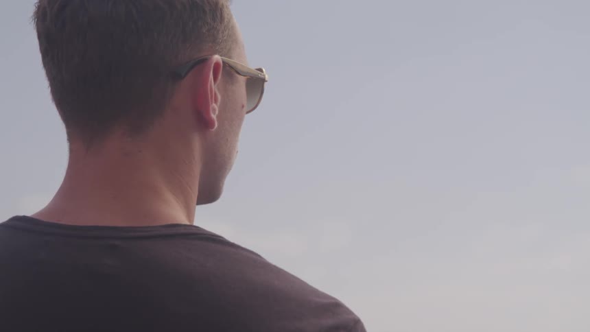 Man wearing sunglasses looks around on a cloudy day