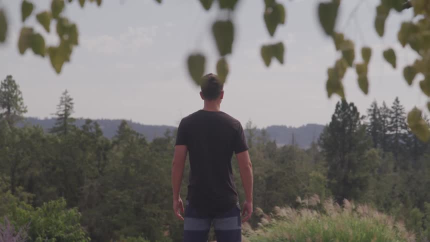 A young man stands and looks our across the landscape