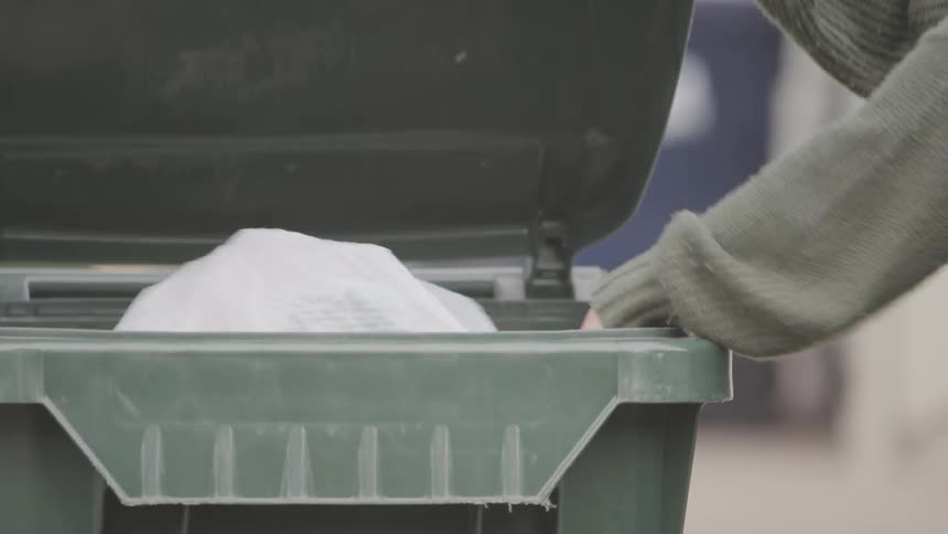 A woman throwing trash in to the bin