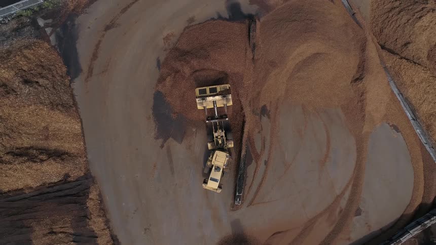 A large earth moving machine works on a large pile of dirt