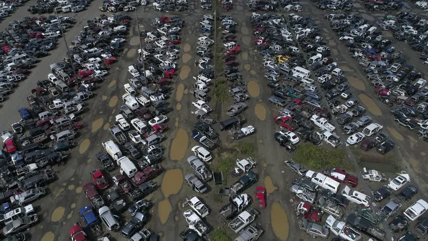 Dozens of vehicles are parked diagonally in a field