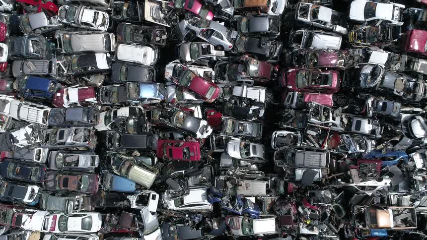 Man vehicles sit in a pile in a junkyard