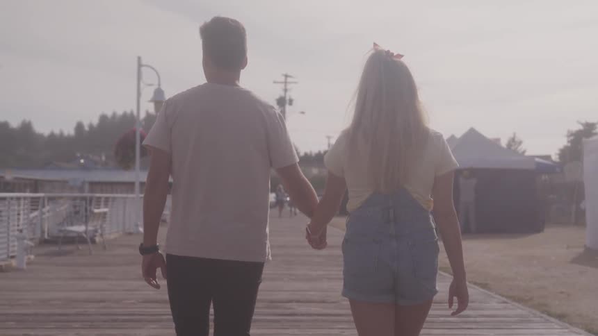 Man and woman are holding hands and walking on the beach