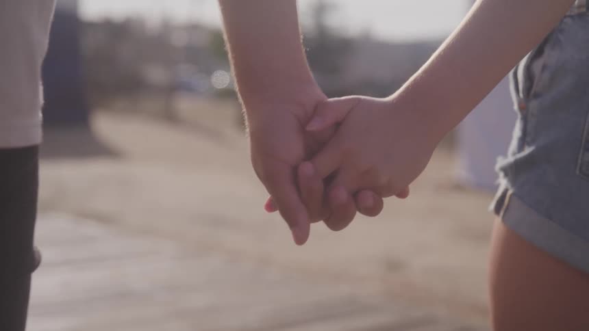 A young couple walks along holding hands