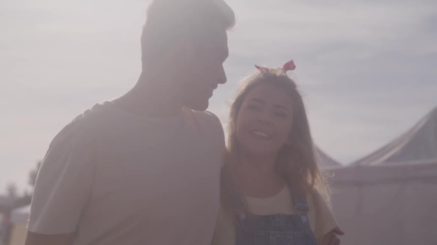 A man and woman walk arm in arm outside