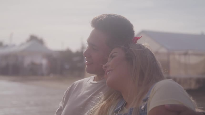 A man and woman lean against each other on the beach