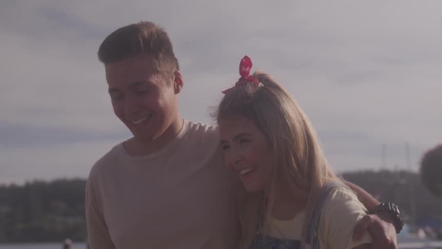 A boy leans over and kisses a girl on the forehead