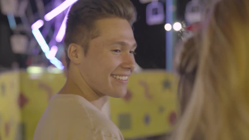 A teenager walks along with his girlfriend and laughs