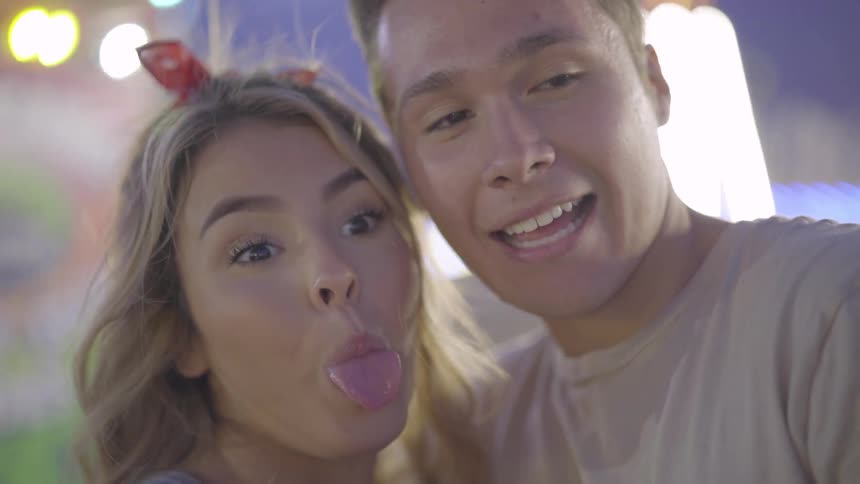 A couple with heads together smile and stick their tongues out