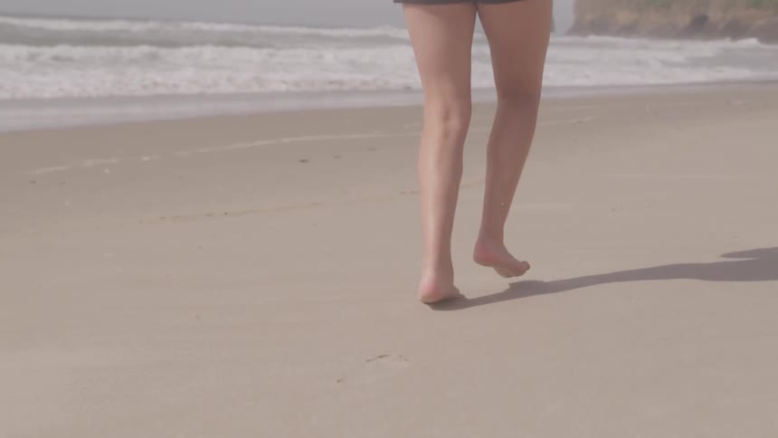 A woman in short shorts running on the beach