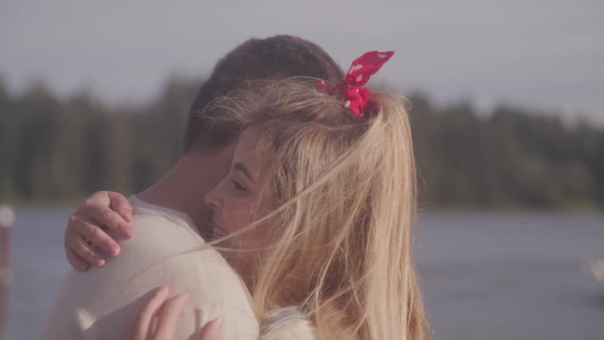 A man and woman embrace by the lake