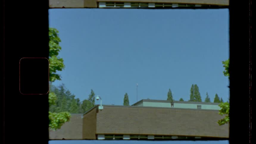 A drab building sits surrounded by trees