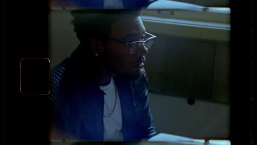 Film footage of a black teenager reading a book in a classroom