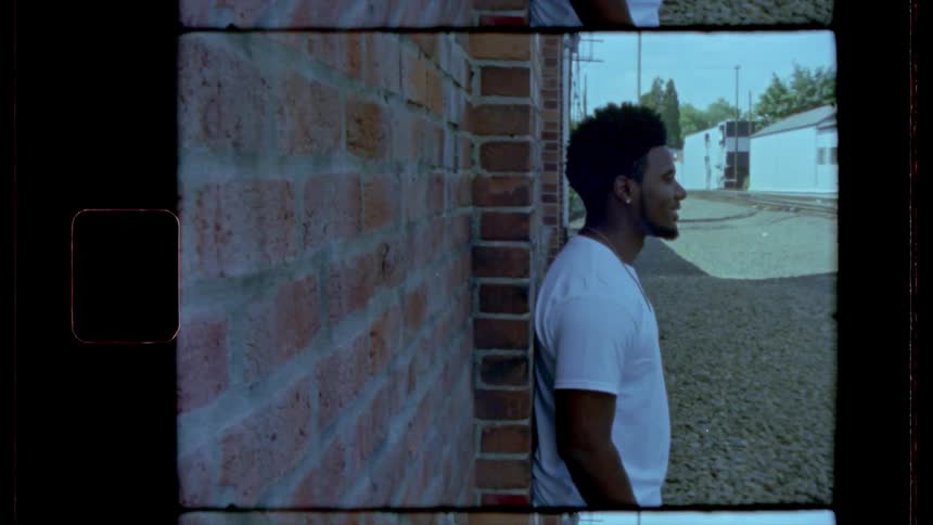 A black man stand in front of a brick wall