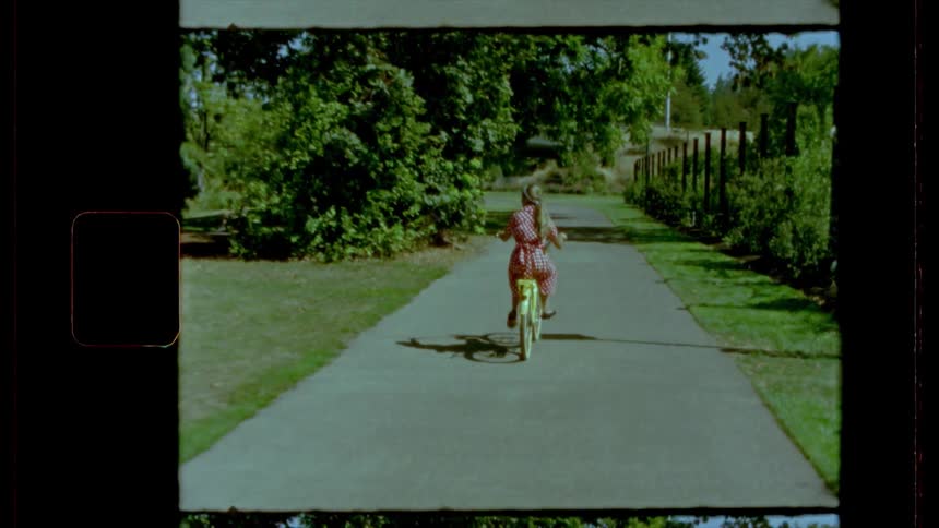 Film footage of a girl riding her bike down a sidewalk