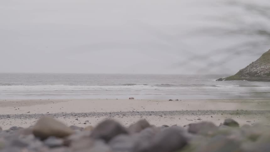Ocean waves come to a sandy shore on a cloudy day